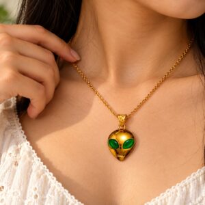 Astra Enigma gold alien pendant with green eyes worn at the neckline on a gold-tone chain
