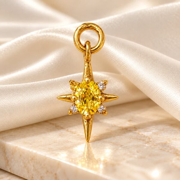 Solara gold-tone starburst pendant with golden-yellow oval stone displayed against ivory satin