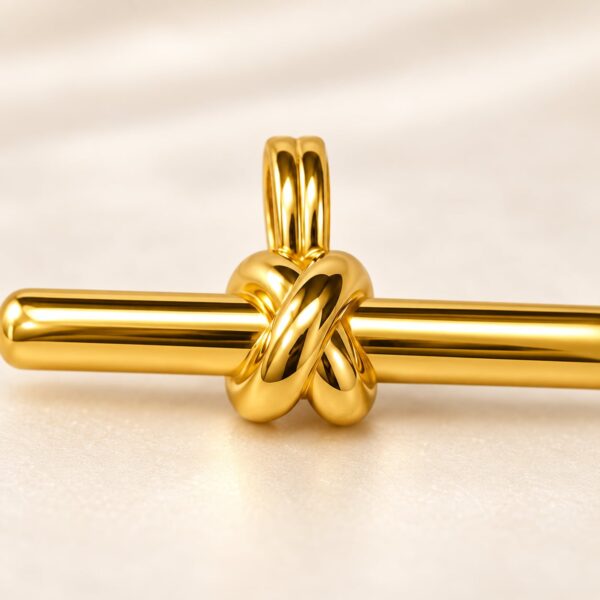 Close-up of sculptural knot and double bail on Aurelia gold-tone bar pendant