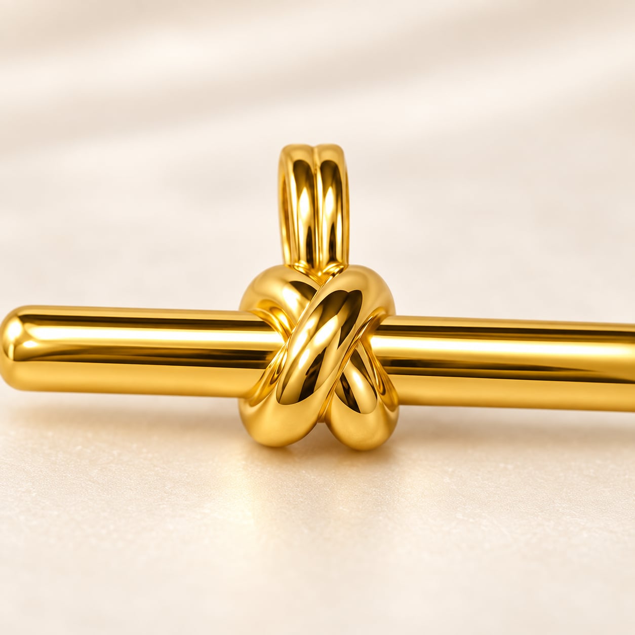 Close-up of sculptural knot and double bail on Aurelia gold-tone bar pendant