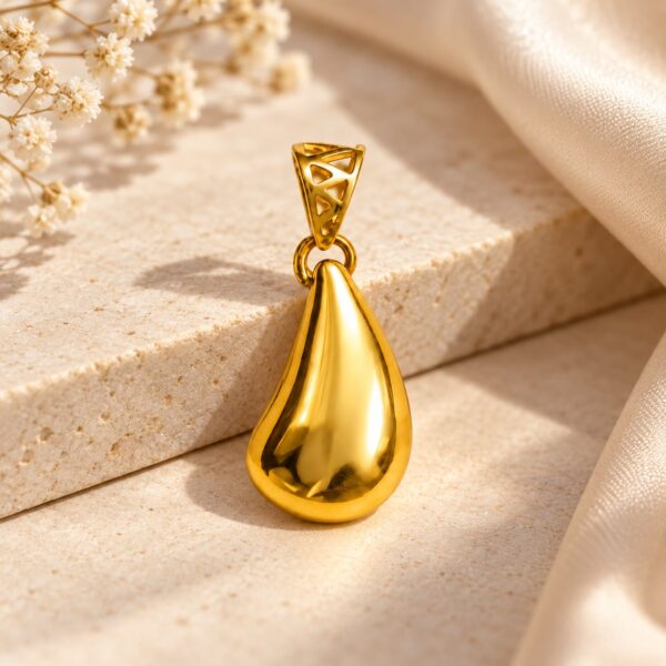 Lifestyle view showing the Aurelia Sculpted Teardrop Pendant styled at the neckline on a fine gold-tone chain. The sculptural teardrop creates a polished focal point against a simple neckline. Pendant sold separately; pictured chain is not included.