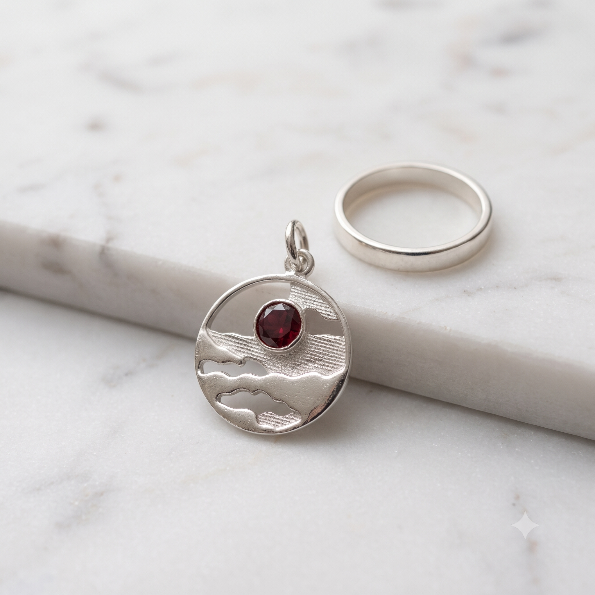 Horizon Solstice Ruby Red CZ sterling silver landscape medallion displayed on white marble