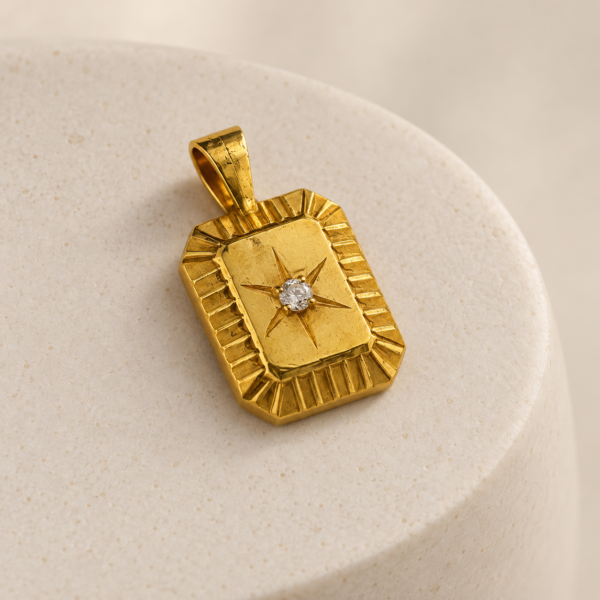 Angled view of Polaris vintage-inspired gold medallion with fluted edges, North Star motif and white CZ