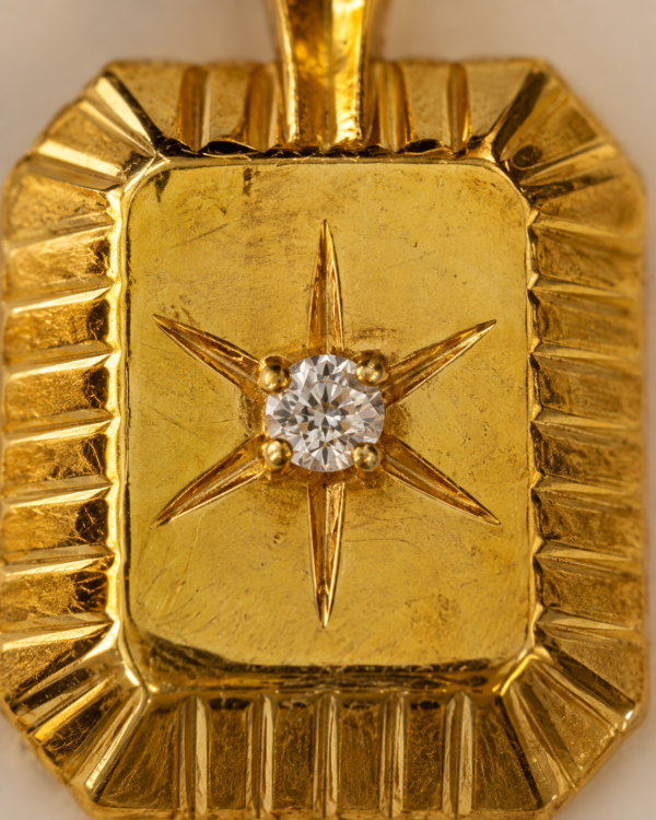 Close-up of Polaris gold medallion with six-point North Star, round white CZ and sculpted fluted border