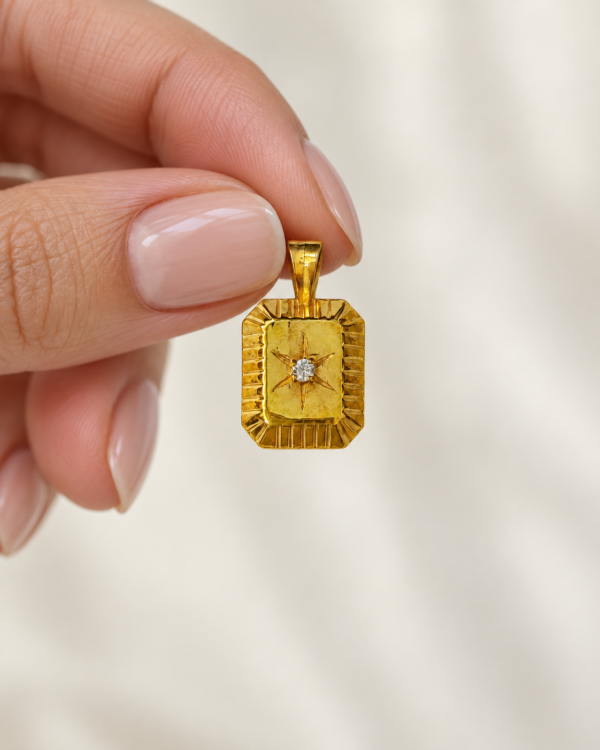 Polaris True North gold vermeil North Star medallion held between fingers to show pendant size and detail