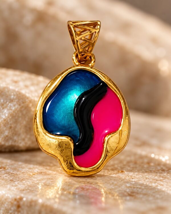 Close-up of Aurora Muse gold-tone pendant showing the geometric bail, metallic blue finish, pink detailing and curved black accent.
