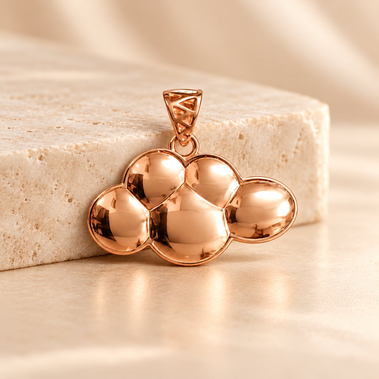 Rose gold Cirrus Cloud 925 silver pendant styled beside warm ivory travertine