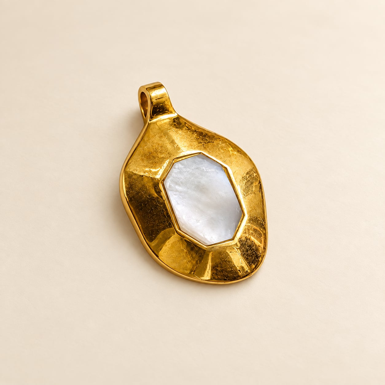Angled view of Solis mother of pearl statement pendant with hammered gold-tone frame and white geometric centre.