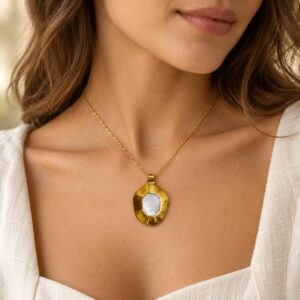 Woman wearing Solis mother of pearl statement pendant on a fine gold-tone chain with a white top.